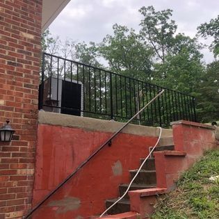 A brick building with stairs leading up to a balcony with a railing.