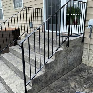A set of stairs with a metal railing on the side of a house.