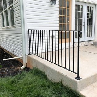 A wrought iron railing is attached to the side of a house.