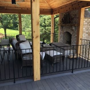 A patio with a fireplace and chairs under a wooden roof.