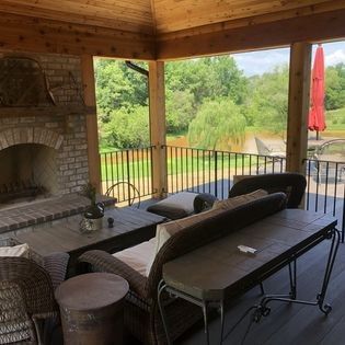 A porch with a fireplace , couch , table and chairs.