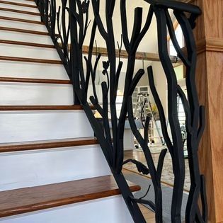 A staircase with a black railing that looks like a tree branch.