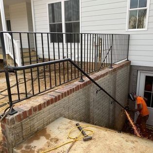 A man is working on a railing on the side of a house.