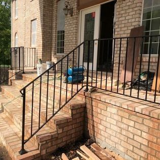 A brick house with a metal railing and stairs