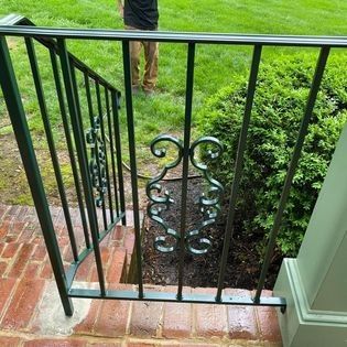 A man is standing next to a wrought iron railing on a set of stairs.
