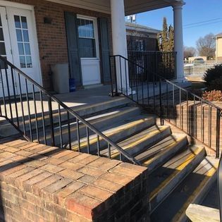 A set of stairs leading up to a brick building with a metal railing.