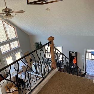 A staircase in a house with a wrought iron railing and a ceiling fan.