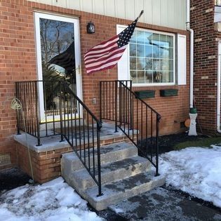 An american flag is flying in front of a brick house.