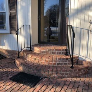 A brick porch with stairs leading up to the front door of a house.