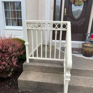A white railing is on the steps of a house.