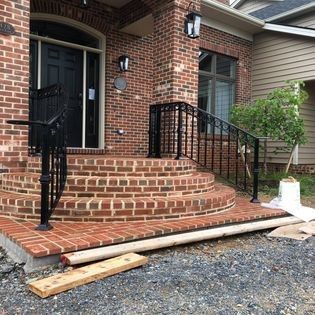 A brick house with stairs and a wrought iron railing.