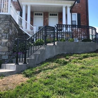 A house with stairs leading up to the front door and a wrought iron railing.