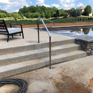 A hose is sitting on the ground next to a staircase leading to a pool.