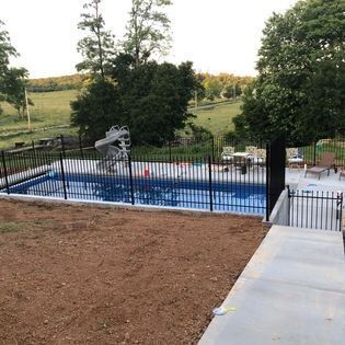 A large swimming pool surrounded by a fence and a slide.