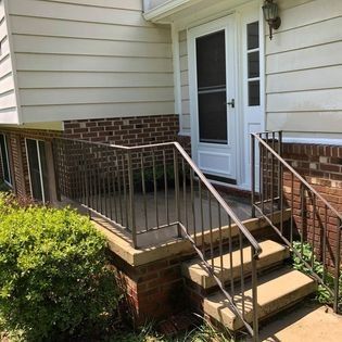 A brick house with a screened in porch and stairs leading up to it.