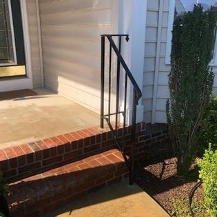 There is a black railing on the side of the house.