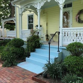 A yellow house with a porch and stairs painted blue
