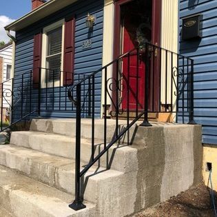 A blue house with a red door and stairs with a black railing.