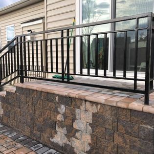 A black railing is sitting on top of a brick wall next to a house.