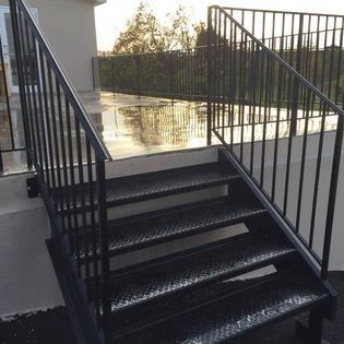 A set of stairs with a metal railing leading up to a balcony.