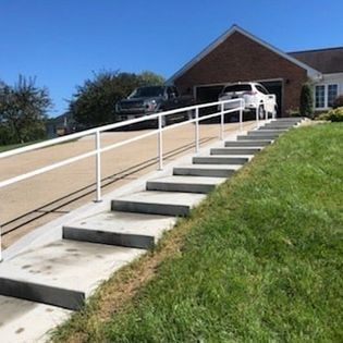 A car is parked on the side of the road next to a set of stairs leading up to a house.