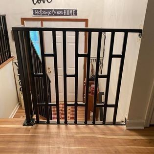 A black metal railing is sitting on top of a wooden floor next to a staircase.