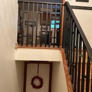 A staircase with a wreath hanging on the door and a black railing.
