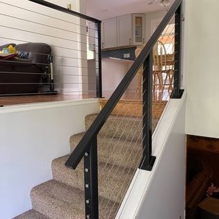 A staircase with a black railing and a carpeted staircase in a house.