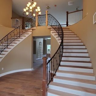 A curved staircase in a house with a chandelier hanging from the ceiling