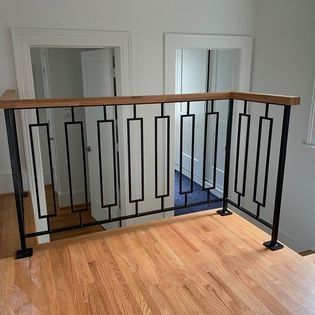 A wrought iron railing with a wooden handrail on a wooden floor in a room.