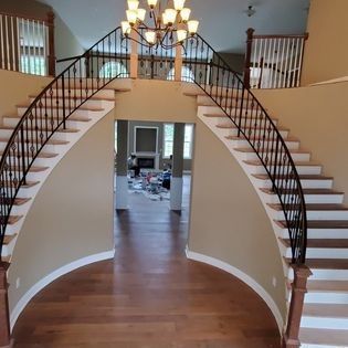 A curved staircase in a house with a chandelier hanging from the ceiling.