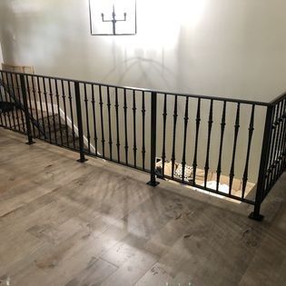 A wrought iron railing surrounds a staircase in a house.