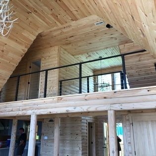 A man is standing on a balcony in a log cabin.
