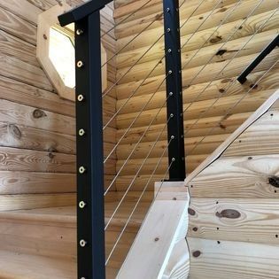 A wooden staircase with a black railing in a log cabin.