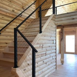 A wooden staircase with a black railing in a log cabin.