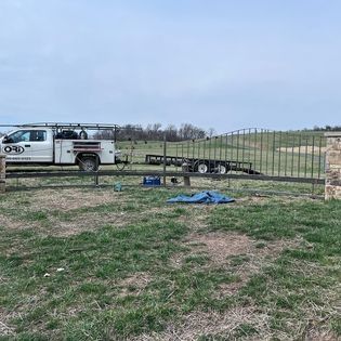 A white truck is parked in a grassy field next to a trailer.