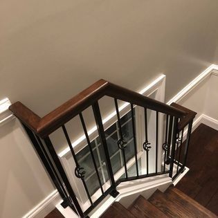 An aerial view of a staircase with a wrought iron railing and wooden handrails.