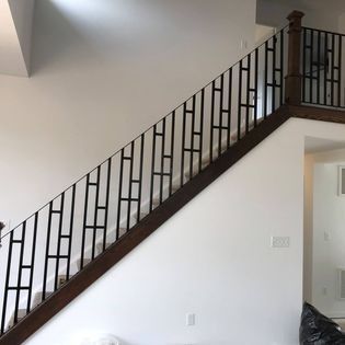A wooden staircase with a wrought iron railing in a living room.