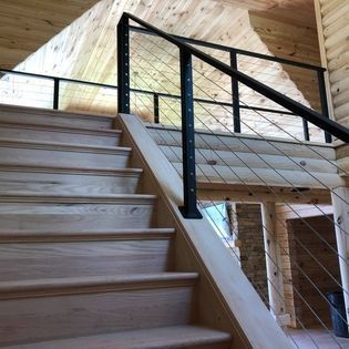 A wooden staircase with a metal railing in a log cabin.
