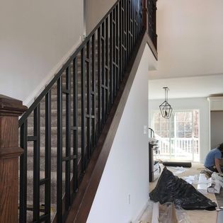 A man is working on a staircase in a house.