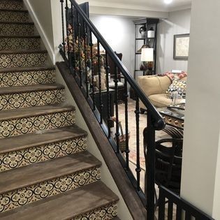A set of stairs leading up to a living room with a black railing.