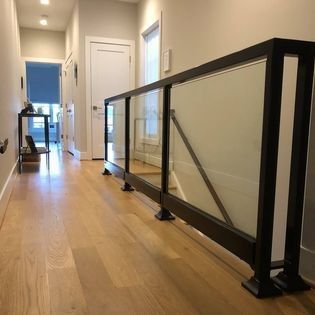 A hallway with hardwood floors and a glass railing.
