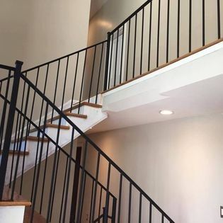 A staircase with a black railing leading up to the second floor of a house.