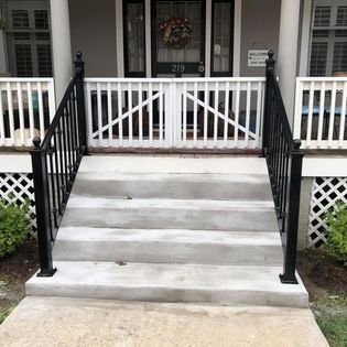 A house with a porch and stairs with a black railing.