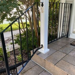 A black metal railing on a porch next to a white post.