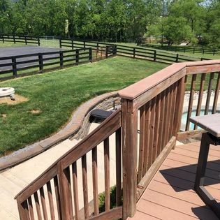 A wooden deck with stairs leading up to it and a fence in the background.