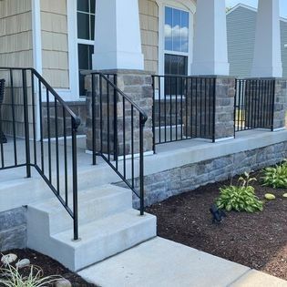 A front porch with stairs and a black railing
