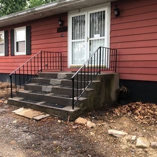 A red house with a black railing on the front steps.