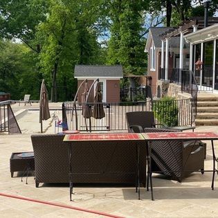 A patio with a couch , chairs , umbrellas and a table.