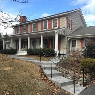 A large house with a large porch and stairs leading up to it